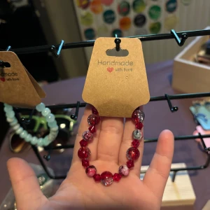 Handgjort rött pärlarmband - Unikt armband med röda och marmorerade pärlor i olika former. Pärlorna är glittriga och vissa har inslag av vitt och grått, vilket ger en cool kontrast. Perfekt accessoar för att lyfta din stil med färg och personlighet.