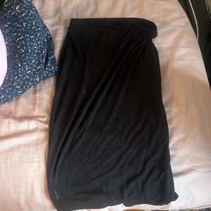 Svart långkjol från ASOS, stl 38 - Enkel och stilren svart långkjol från ASOS i storlek 38. Kjolen har en rak och flowy passform som sitter snyggt i midjan. Perfekt att styla med sneakers eller boots för en chill vibe.