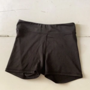 Svarta sportshorts från H&M - Svarta, tighta sportshorts från H&M med enkel design och stretchigt material. Perfekta för träning eller sportaktiviteter. Midjan är elastisk och shortsen har inga synliga detaljer eller fickor.