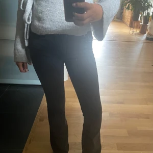 Svarta bootcut jeans med mid/low midja - Säljer ett par svarta jeans med bootcut-modell och mid/low midja. Jeansen har klassiska fickor både fram och bak och är i stretchigt denimtyg som sitter snyggt över höfterna och låren. Perfekta för dig som gillar en tidlös och clean look.