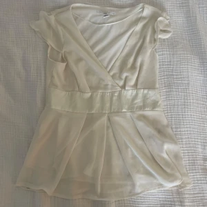 Vit omlottblus från H&M - Superfin vit blus från H&M med omlott framtill och markerad midja. Strl M