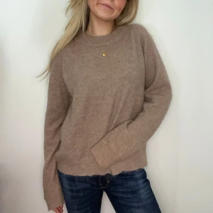 Beige stickad tröja - Mysig beige stickad tröja med rund hals och långa ärmar. Perfekt för kyligare dagar och enkel att matcha med jeans eller kjol.