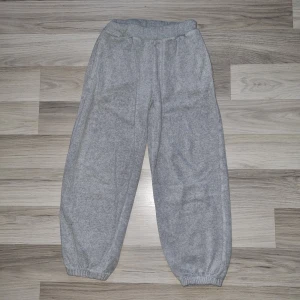 Grå mjukisbyxor - Säljer ett par bekväma grå mjukisbyxor från. Byxorna har elastisk midja och muddar vid bensluten för en skön passform. Perfekta för en avslappnad dag hemma eller på gymmet.