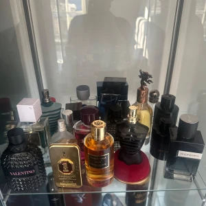 Parfymkollektion med olika märken kom med bud! - En samling av exklusiva parfymer från olika märken. Flaskorna har unika och stilfulla designer, inklusive en svart flaska från Valentino med en texturerad yta och en guldflaska med en elegant etikett. Perfekt för den som vill ha en varierad doftgarderob.