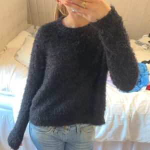 Svart fluffig tröja - Mysig svart fluffig tröja med lång ärm. Perfekt för kyliga dagar och ger en stilren look. Passar bra till jeans eller kjol.