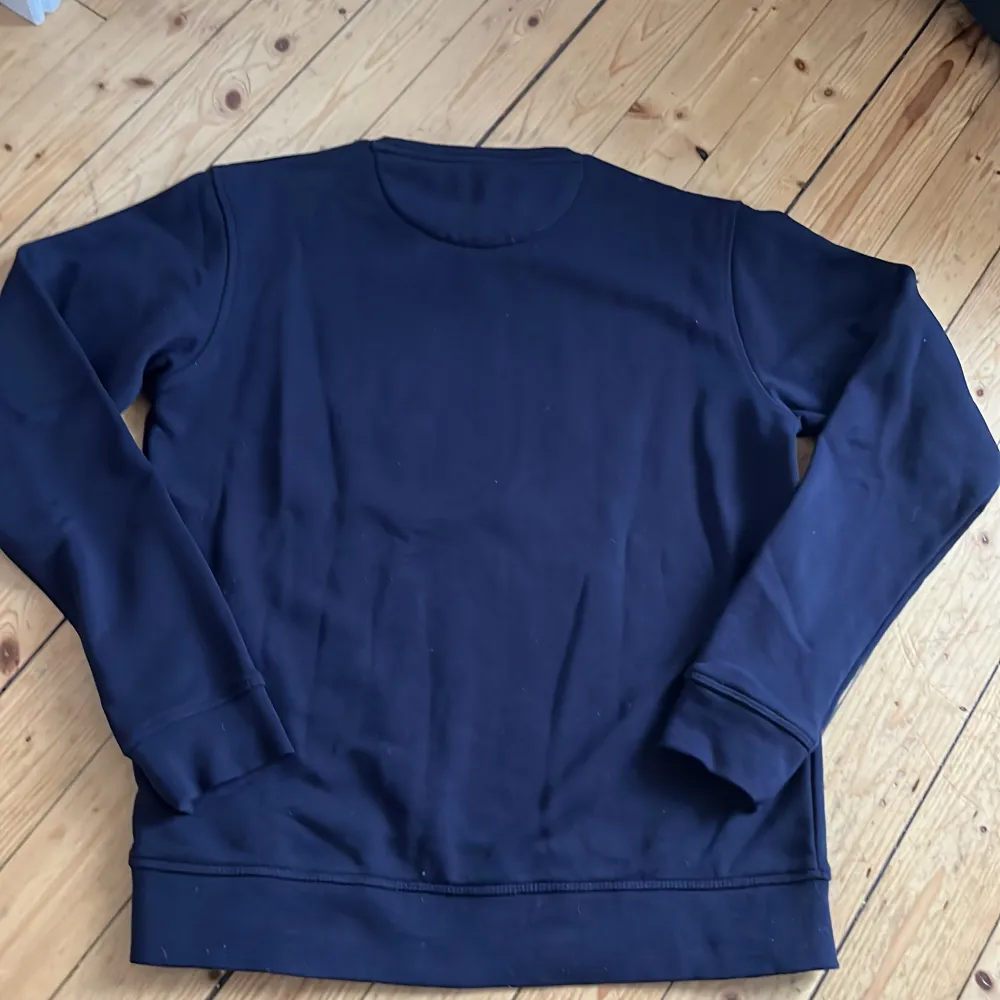 Säljer en stilren mörkblå sweatshirt från GANT med deras logga tryckt i vitt på bröstet. Tröjan har långa ärmar och en klassisk rund halsringning. Perfekt för en avslappnad look.. Neuletakit & Villapaidat.