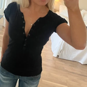 T-shirt - T-shirt med knappar, har ett litet hår som man inte tänker på vid armen