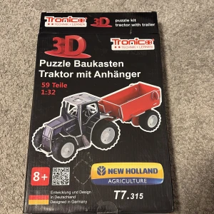3D Pussel Byggsats Traktor med Vagn - Byggsats för en 3D-pussel traktor med vagn, modell New Holland T7.315. Innehåller 59 delar i skala 1:32. Tillverkad av tryckt kartong och plast, med detaljerade instruktioner. Perfekt för barn över 8 år som gillar att bygga och leka med modeller. Kartongen är öppnad 2 gånger för att fota allting. Annars är allting inplastat och orört. 