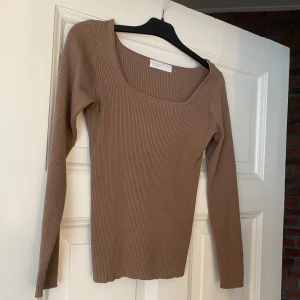 Beige ribbad tröja - Säljer en stilren beige ribbad tröja med lång ärm och fyrkantig halsringning. Perfekt för lager-på-lager eller som den är. Enkelt att matcha med olika outfits.