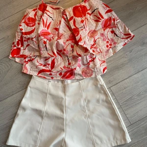 Set kläder  - En tröja och snygga vita shorts från Baby, You Own My Heart. Perfekta för sommardagar med en stilren design och hög midja. Matcha med en färgglad topp för en fräsch look.