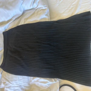 Svart ribbad kjol MQ - Snygg svart ribbad kjol i en klassisk design från MQ. Perfekt för en stilren look. Den är gjord av ett mjukt och stretchigt material som ger en bekväm känsla hela dagen. Lite dammig på bilden så inga fläckar! Nästan oanvänd