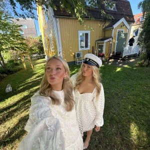 Vit spetsklänning - Elegant vit spetsklänning med långa ärmar och v-ringad design. Perfekt för studenten. Klänningen har ett vackert blommigt mönster och en romantisk känsla.  