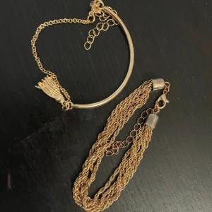 Guldarmband med kedjedetaljer - Elegant guldarmband med flera kedjor och justerbar kedja för perfekt passform. Armbandet har en stilren design med en liten tofsdetalj som ger en unik touch.