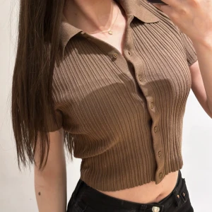 Ribbad topp från H&M Divided - Brun ribbad topp från H&M Divided. Toppen har korta ärmar och knappar framtill, i storlek xs. 