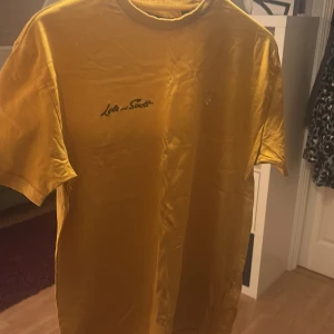 Gul t-shirt från Lyle & Scott - Säljer en gul t-shirt från Lyle & Scott med broderad logga på bröstet. T-shirten har en boxig passform och är kortärmad, perfekt för en avslappnad stil.