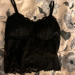 Svart spetslinne - Säljer ett svart spetslinne med justerbara axelband. Har aldrig använts och är därför i riktigt bra skick och inget slitage.