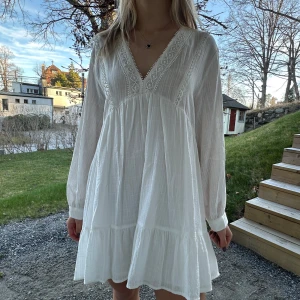 Vit klänning från Zara - Säljer en söt vit klänning från Zara med v-ringning och spetsdetaljer med prislappen kvar. Den är i storleken L men är mer som en M/S. Klänningen har långa ärmar och en luftig passform, perfekt för varmare dagar. Den är tillverkad i ett lätt och bekvämt material. Pris går att diskutera!