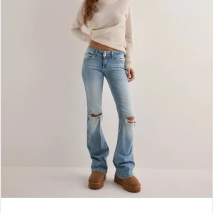 Lågmidjade Ljusblå bootcut jeans med slitningar - Snygga ljusblå bootcut jeans med slitningar vid knäna. De har en klassisk femficksdesign och en låg midja.jag har klippt av dom längst ner så dom passar mig som är 160! Knappast aldrig använda, slutsålda och  ny pris 699