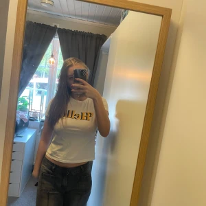 Vit kortärmad t-shirt med tryck - Säljer en vit kortärmad t-shirt med tryck i gult. T-shirten har en tight passform och är perfekt för en avslappnad stil. Passar bra till jeans eller shorts.