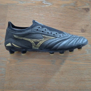 Fotbollsskor från Mizuno. Mizuno Morelia Neo IV Beta made in Japan FG/AG Aurum guld/svart - Fotbollsskor från Mizuno,  svarta med gulddetaljer.  Storlek 40, innermått 24,3cm.