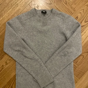 Grå tröja från Uniqlo - Säljer en stilren grå tröja från Uniqlo. Tröjan är långärmad och har en klassisk rund halsringning. Perfekt för kyligare dagar.