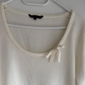 Vit tröja från InWear - Säljer en stilren vit tröja från InWear med en söt rosett vid halsringningen. Tröjan har trekvartsärmar och är tillverkad i ett mjukt material som ger en bekväm passform. Perfekt för en elegant och avslappnad look.