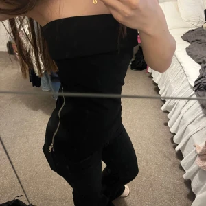 Svart axelbandslös topp - Snygg svart off sholder topp med dragkedja på sidan. Storlek xs men skulle även säga att den passar strl s då den är väldigt stretchig.