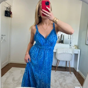 klänning - Otroligt vacker blå mönstrad sommar-klänning med paisleymönster. Klänningen har en v-ringad design och volangdetaljer vid axelbanden. Perfekt för sommarens alla tillfällen!🦋 från bodyflirt i storlek Xs 