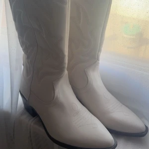 Vita cowboy boots - Snygga vita cowboy boots med spetsig tå och dekorativa broderier.  Helt oanvända köptes för ett tag sen men har ba legat å tagit plats i mitt rum. Nypris var ca 900kr 