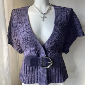Lila stickad kofta med bälte - Säljer en snygg lila stickad kofta med korta ärmar och ett brett bälte i midjan. Den är i fint skick - trots lite noppror och slitningar på bältet. Uppskattar till storlek M 💜