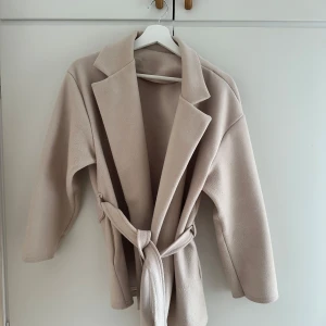 Beige Kappa - En beige kappa från märket missäy. Storlek S. I väldigt bra skick och perfekt nu till våren