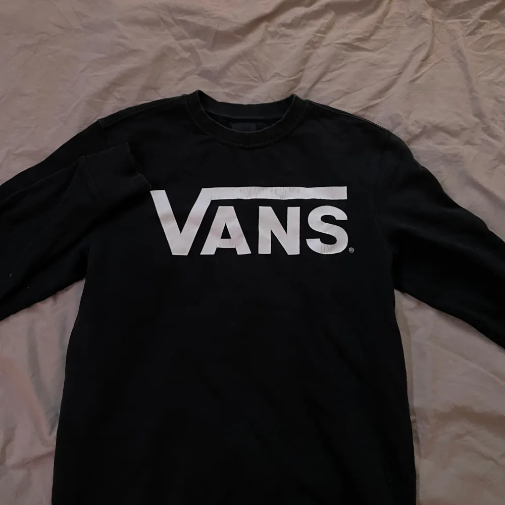 Säljer en svart långärmad tröja från Vans med deras ikoniska logga i vitt på bröstet.. Neuletakit & Villapaidat.