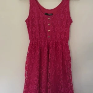 Rosa spetsklänning från Atmosphere 36 - Säljer en  rosa spetsklänning från Atmosphere. Klänningen är ärmlös och har knappar framtill. 