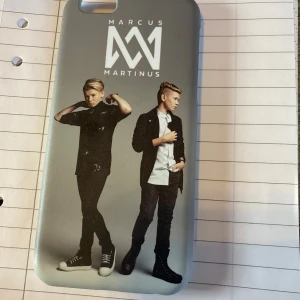 Mobilskal med Marcus & Martinus motiv - Snyggt mobilskal med motiv av Marcus & Martinus. Skalet är grått med bilder av artisterna i helfigur och deras logotyp ovanför. Perfekt för fans som vill ge sin telefon en personlig touch.