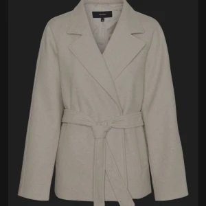 Beige kappa med bälte -  Jag säljer denna kappa i storlek M efterosm den inte komm till användning prislappen sitter öven kvar orginal priset är 700kr jag går ner till 550 kr men priset kan diskuteras . Det är en ellegant beige kappa från Vero moda med knytbälte i midjan. Den har en klassisk krage och långa ärmar, perfekt för kyligare dagar. Stilren och tidlös design som passar till många tillfällen.