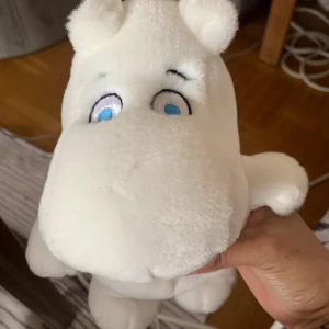 Mumin mjukisdjur - Säljer ett vitt Mumin mjukisdjur med blå ögon och små öron. Gosedjuret är gjort av mjukt tyg och har en rund kropp, kort svans och broderade detaljer i ansiktet. Perfekt för alla som gillar Mumin och vill ha en mysig kompis.
