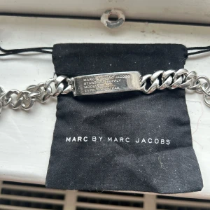 Silverfärgat armband från Marc by Marc Jacobs - Säljer ett chunky armband i silverfärg från Marc by Marc Jacobs. Armbandet har en kraftig kedja och en rektangulär platta med ingraverad text samt en liten rund bricka vid låset. Perfekt statement-accessoar. Titta gärna min profil och följ mig ❤️ . Hämta i Göteborg 