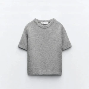 Grå stickad tröja från Zara - Säljer en enkel och stilren grå stickad tröja från Zara. Tröjan har korta ärmar, rund halsringning och mjuk känsla. Perfekt för lager-på-lager eller som den är under svalare dagar. Aldrig använd alltså i nyskick! Liten i storleken 