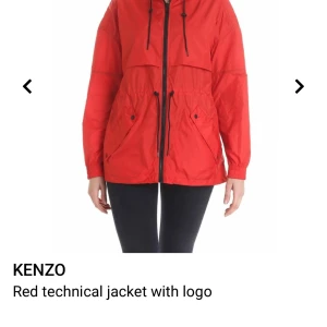 Röd teknisk jacka från Kenzo - Säljer en röd teknisk jacka från Kenzo med svart logotyp på ryggen. Jackan har huva, dragkedja framtill, justerbar midja med snörning och två stora fickor. Perfekt för dig som vill ha en sportig och snygg look.