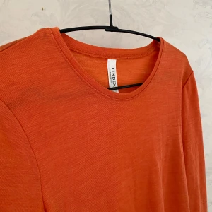 Orange långärmad merinoulltröja från Lindex - Säljer en orange långärmad tröja från Lindex i 100% merinoull. Oanvänd!