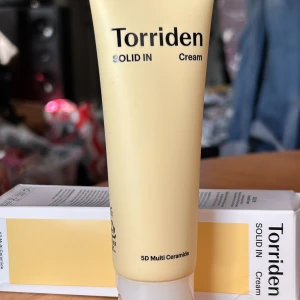 Torriden Solid in cream! - Torriden Solid in cream. 70 ml. Plomberad.   TORRIDEN SOLID-IN Ceramide Cream är en kräm med en effektiv blandning av fem typer av ceramider, fettsyror, kolesterol, pantenol och allantoin.  Den mjuka, smöriga konsistensen glider lätt på huden och håller den återfuktad hela dagen. Passar alla hudtyper. Särskilt lämplig för torr och känslig hud.
