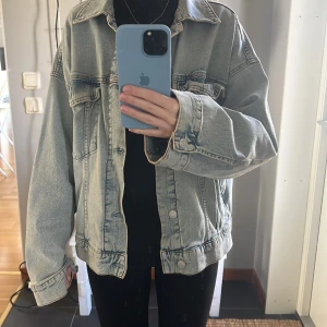 Oversized ljusblå jeansjacka - Säljer en oversized ljusblå jeansjacka med klassisk krage och knappar framtill. Jackan har två bröstfickor med lock och knapp samt sömdetaljer som ger en snygg vintagekänsla. 
