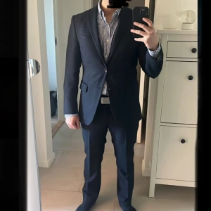 Oscar Jacobson kostym - Säljer en klassisk mörkblå kostym från Oscar Jacobson, modell Heritage. Kostymen har en stilren kavaj med två knappar och matchande byxor. Perfekt för formella tillfällen och student. Kavajen och byxor är i nyskick, använt vid enstaka tillfällen och med inga tecken på användning. Nypris ca 6000, mitt pris: 1150 kr. Storleken är 46, vilket motsvarar S, passar ca 175 cm. Stilren och klassisk, perfekt för formella tillfällen.