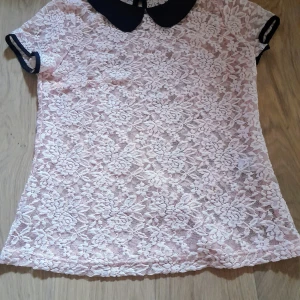 Nwot Ljusrosa spetsblus med svart krage från Allegra K - Säljer en söt rosa blus i spets från Allegra K med korta ärmar och kontrasterande svart krage. Blusen har ett blommigt spetsmönster och svarta detaljer vid ärmsluten. Perfekt för dig som gillar romantisk stil! Ny utan lapp 