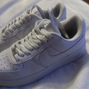 Vita Nike Air Force 1 sneakers - Klassiska vita Nike Air Force 1 sneakers med vit sula och snörning. Skorna är köpta i Kosovo och är använda kanske 5 gånger.