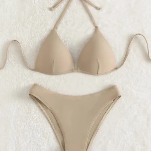 Beige bikini med knyt - Stilren beige bikini med trekantsöverdel och knytband i nacken och ryggen. Underdelen har en klassisk, något hög midja. Tillverkad i mjukt material som känns bekvämt mot huden. Perfekt för strand eller pool.