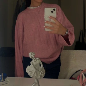 Rosa stickad tröja - Mysig rosa stickad tröja med rund hals och långa ärmar. Tröjan har en avslappnad passform och ribbade muddar vid ärmslut och nederkant. Perfekt för lager-på-lager och passar till både jeans och kjol.