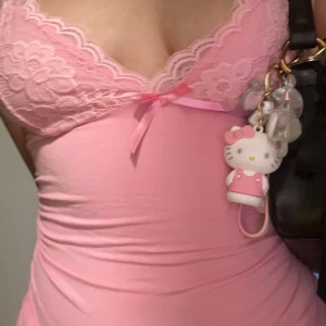 Rosa spetstop med rosett - Söt rosa top med spets upptill och liten rosett i mitten. Top har en figurnära passform och är ärmlös, perfekt för sommarens varma dagar.