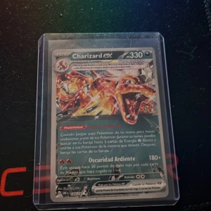 Charizard ex Pokémonkort - Säljer ett Charizard ex Pokémonkort med holografisk yta. Kortet är på spanska och har 330 HP. Det ligger i ett genomskinligt plastfodral för extra skydd. Perfekt för samlare eller Pokémon-fans!