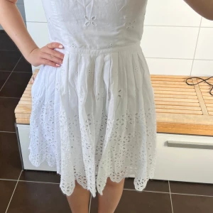 Vit klänning med broderade detaljer från LOFT - Superfin vit klänning från New York från butiken LOFT. Fina detaljer med  broderade blommor och hålmönster, och dragkedja på sidan. Klänningen har en markerad midja och utställd kjol i kort längd. Den passar storlek S (jag är 163 för referens) och är helt ny med lappen kvar, jag köpte den för 1000 kr. Tänkte använda till studenten så den passar bra till skolavslutning. Sista bilden visar hur jag hade tänkt klippa av underklänningen lite för att den skulle bli lite mer gneomskling vid benen💕💕